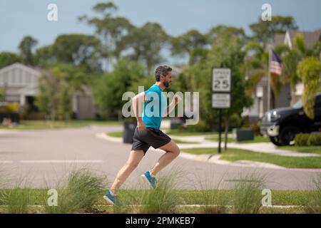 Beau homme d'âge moyen traversant le quartier américain. Homme sportif en plein air. Un mode de vie sain. Jogging actif et sain en extérieur. Banque D'Images