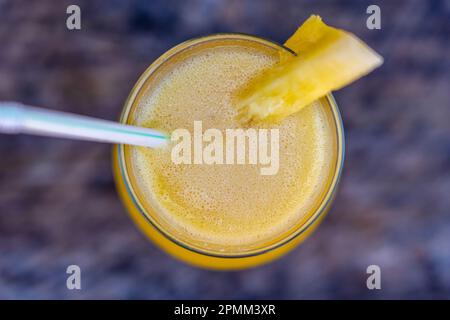 Jus d'ananas fraîchement pressé dans un gobelet en verre sur la table en bois de fond, vue du dessus. Île de Zanzibar, Tanzanie, Afrique de l'est. Gros plan Banque D'Images