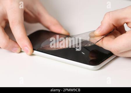 L'homme retire l'ancien verre de protection fissuré du téléphone. Verre de protection cassé Banque D'Images