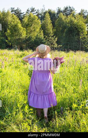 portrait d'une fille dans un champ fleuri au soleil au coucher du soleil Banque D'Images