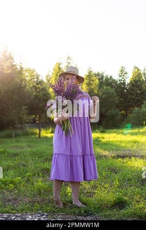 portrait d'une fille dans un champ fleuri au soleil au coucher du soleil Banque D'Images