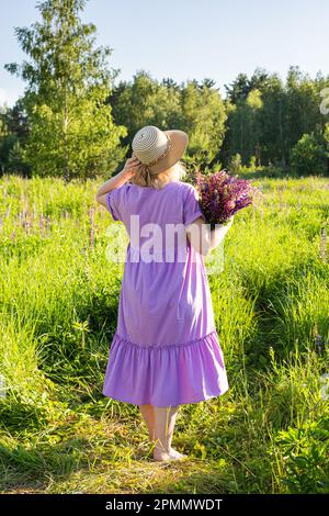 portrait d'une fille dans un champ fleuri au soleil au coucher du soleil Banque D'Images