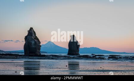 Vue sur les trois Sœurs et le Mont Taranaki au coucher du soleil. Plage de Tongaporutu. Taranaki. Nouvelle-Zélande. Banque D'Images