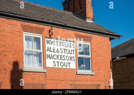 Vieux peint Whitbread's Ale et Stout, Mackeson's Stout signe publicitaire sur la maison de brique rouge / mur de pub, Somerby, Leicestershire, Royaume-Uni Banque D'Images