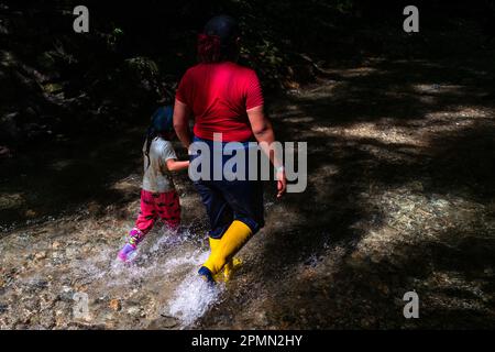 Une immigrante équatorienne, accompagnant sa fille, marche à travers le fleuve dans la jungle dangereuse du fossé Darién entre la Colombie et Panamá. Banque D'Images