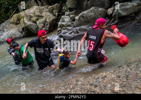 Une famille de migrants équatoriens, s'aidant les uns les autres, traverse la rivière dans la jungle dangereuse du fossé Darién entre la Colombie et Panamá. Banque D'Images