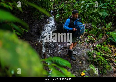 Un migrant équatorien monte sur un sentier rocheux le long d'une cascade dans la jungle sauvage et dangereuse de l'écart Darién entre la Colombie et Panamá. Banque D'Images