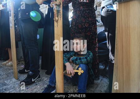 Jérusalem-est, Israël. 14th avril 2023. Un enfant chrétien orthodoxe porte une petite croix en bois le long de la via Dolorosa (voie de souffrance) dans la vieille ville de Jérusalem pendant la procession du Vendredi Saint orthodoxe avant le samedi Saint demain. Les pèlerins chrétiens ont pris part à des processions en chemin car, selon la tradition, Jésus-Christ a porté la croix le dernier jour avant sa crucifixion. (Photo de Saeed QAQ/SOPA Images/Sipa USA) Credit: SIPA USA/Alay Live News Banque D'Images