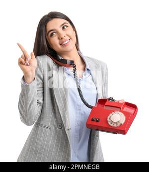 Jolie jeune femme parlant par téléphone et pointant vers quelque chose sur fond blanc Banque D'Images