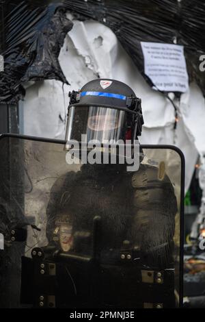 Julien Mattia / le Pictorium - 12th jour de mobilisation contre la réforme des retraites à Paris, 13 avril 2023 - 14/4/2023 - France / Paris / Paris - Portrait d'un policier devant un panneau d'affichage vandalisé lors de la mobilisation contre la réforme des retraites, à Paris, le 13 avril. Banque D'Images