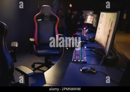 Moniteurs d'ordinateur et claviers sur la table dans le club de jeu flou, image de stock Banque D'Images