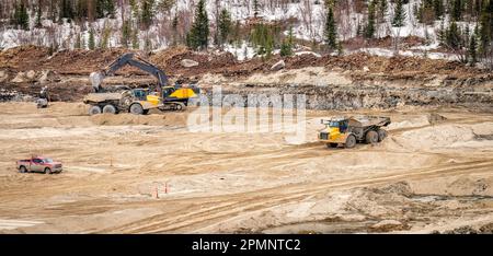 Les tombereaux et les pelles hydrauliques effectuent des travaux d'excavation pendant la construction d'un nouvel étang à résidus Banque D'Images