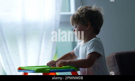 L'enfant joue avec un tableau magnétique à la maison. Scène franche de développement de style de vie d'enfance Banque D'Images