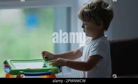Petit garçon jouant avec Magnetic Drawing Board Erasable pour les enfants. Développement du mode de vie de l'enfance Banque D'Images