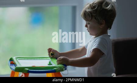 Petit garçon jouant avec Magnetic Drawing Board Erasable pour les enfants. Développement du mode de vie de l'enfance Banque D'Images