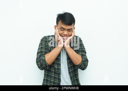 Un jeune homme asiatique couvrant ses oreilles en utilisant les doigts pour éviter le bruit Banque D'Images