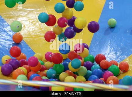 Un ensemble de boules en plastique colorées est dispersé et empilé les unes sur les autres dans un grand puits de balle, créant un environnement dynamique et amusant Banque D'Images
