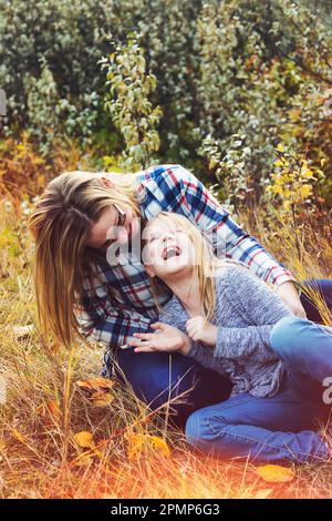 Mère et fille passent du temps ensemble à l'extérieur, jouant et riant ensemble dans un parc en automne; Edmonton, Alberta, Canada Banque D'Images