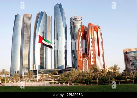 le drapeau national des émirats arabes unis (eau) flotte dans le ciel devant de grands bâtiments à abu dhabi Banque D'Images