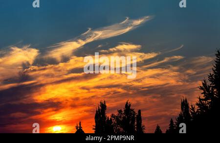 Des nuages brillants et colorés au coucher du soleil avec des silhouettes et un ciel bleu au-dessus; Calgary, Alberta, Canada Banque D'Images