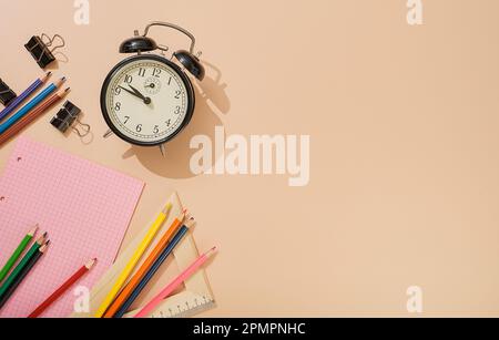 Prêt à retourner à l'école, les sujets de l'école sur un fond léger de couleur chair. Blocs-notes, stylos, crayons, réveil et autres outils. Bannière avec pla Banque D'Images