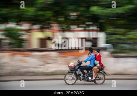 Motocycliste et son cavalier parlant tous les deux sur un téléphone portable en route ; Luang Prabang, Laos Banque D'Images