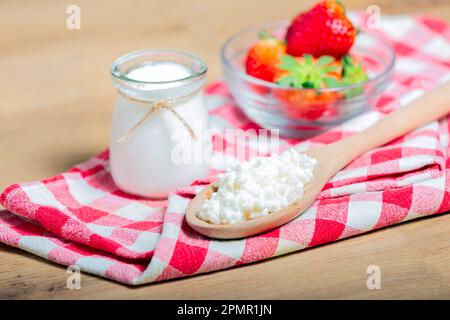 Grains de kéfir dans une cuillère en bois devant des tasses de yaourt de kéfir. Le kéfir est l'un des meilleurs aliments de santé disponibles fournissant des probiotiques puissants. Banque D'Images
