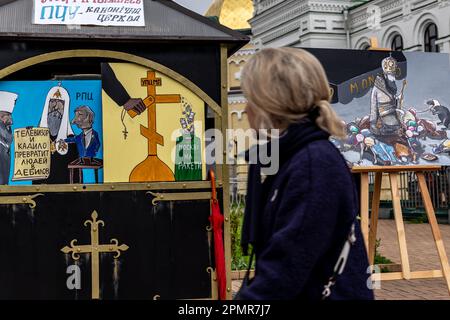 Une femme ukrainienne regarde des images qui illustrent le patriarcat russe comme outil de guerre de Poutine lors des célébrations du Vendredi Saint devant Kiev Pechersk Lavra, la capitale de l'Ukraine le vendredi orthodoxe de Pâques - 14 avril 2023. La plupart des Ukrainiens sont des chrétiens orthodoxes ou des chrétiens catholiques grecs, tous deux observent le rite oriental de Pâques. Kiev reste relativement pacifique alors que l'invasion russe se poursuit et que l'Ukraine se prépare à une contre-offensive printanière pour reprendre les terres ukrainiennes occupées par la Russie. (Photo par Dominika Zarzycka/Sipa USA) Banque D'Images