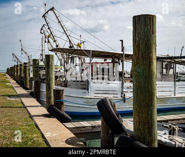 ROCKPORT, TX - 14 FÉVRIER 2023 : une rangée de pillages en bois à la marina avec des bateaux de pêche amarrés par une journée partiellement ensoleillée au Texas. Banque D'Images