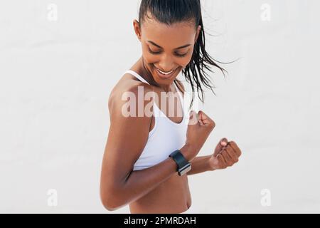 Femme souriante montrant son biceps. Jeune femme heureuse regardant ses muscles sur une main. Banque D'Images