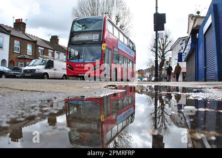 UN BUS LONDONIEN DE E3 SE REFLÈTE DANS LA FLAQUE DE L'INA SUR NORTHFIRLDS AVE, EALING WEST LONDON. Banque D'Images