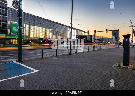 Poznan, Pologne - 2022 juillet : une intersection animée en face de l'entrée de la foire internationale de Poznan après le coucher du soleil Banque D'Images