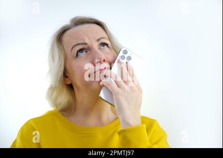 Pensive et pensive jeune 50s femme tenant un smartphone regarder loin perdu sur de tristes pensées attendant la première étape de l'homme, appel ou message texte ou date invitation de l'ami se sent jalousy et inquiet Banque D'Images