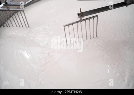 Mélange du lait dans le réservoir de préparation du lait caillé à l'usine de fromage, gros plan. Processus de fabrication de cheesking chauffage du lait Banque D'Images