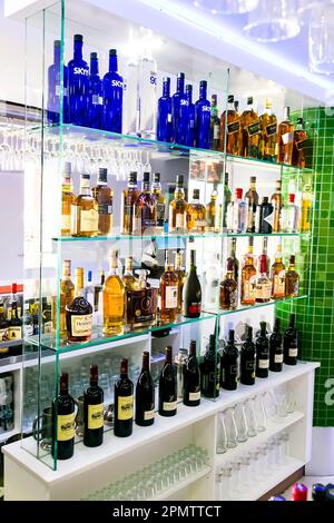 Un bar bien approvisionné avec une variété de bouteilles de liqueur disposées sur des étagères, accompagné de verres à vin et d'autres verres pour servir Banque D'Images
