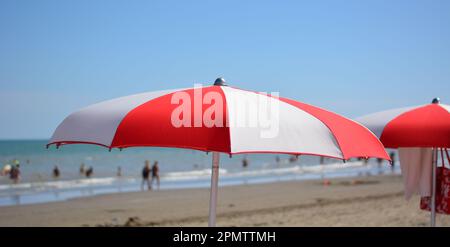 un parapluie blanc et rouge devant les vagues de la mer Banque D'Images