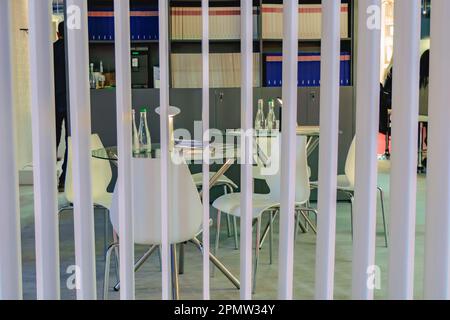 Chaises de bureau blanches et table ronde en verre derrière une cloison. Banque D'Images