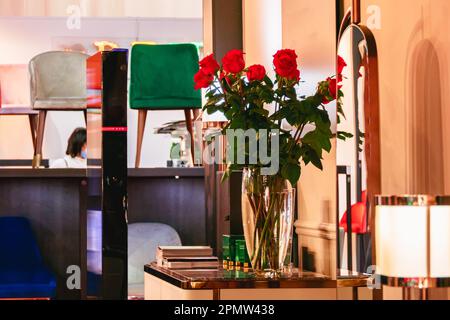 Roses rouges dans un vase en verre transparent sur la table près du miroir. Banque D'Images