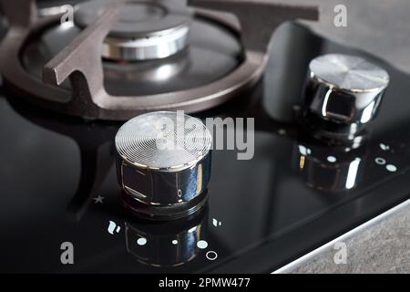 Table de cuisson moderne en verre trempé noir avec deux brûleurs et bouton d'allumage automatique. La casserole en fonte prend en charge la haute pression compacte Banque D'Images