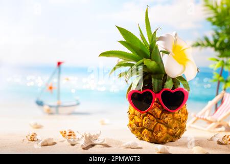 Concept de plage de vacances d'été. Ananas avec lunettes de soleil en forme de coeur. Hipster fruit sur le sable contre la mer. Idée de fête d'été. Banque D'Images