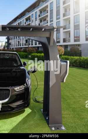 La voiture électrique est chargée à partir d'une station de charge qui prend l'énergie des panneaux solaires. Photo de haute qualité Banque D'Images