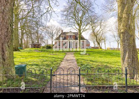 Dorwerd, pays-Bas - 27 mars 2023: Maison pittoresque avec arbres dans le village de Littel Dorkwerd municipalité de Groningen aux pays-Bas Banque D'Images