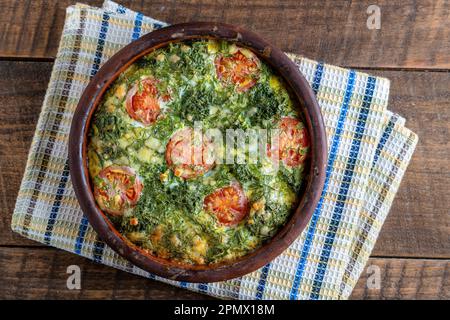 Bol en céramique avec frittata de légumes, simple nourriture végétarienne. Frittata avec oeuf, tomate, poivre, oignon, brocoli vert et fromage sur table en bois, clo Banque D'Images