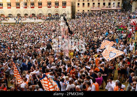 Sienne, Italie - 17 août 2022: Palio di Siena célébration de la victoire sur la Piazza del Campo avec Dappellone et drapeaux de la Contrada de Léocorno. Banque D'Images