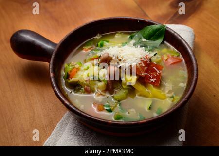 Soupe de légumes italienne minestrone aux haricots et aux pâtes dans un bol rustique en terre cuite avec serviette de table Banque D'Images