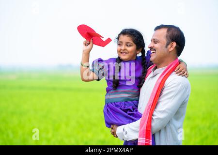 Joyeux village fille enfant jouant avec l'avion jouet tout en père tenant ou portant près de terres agricoles - concept de la relation, l'attention des parents et en bonne santé Banque D'Images