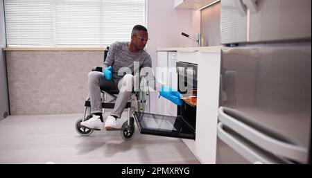 Homme Handicapé Utilisant Un Four À Micro-Ondes Pour La Cuisson Dans La Cuisine Banque D'Images