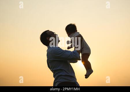 Père heureux tenant bébé nouveau-né jouer avec vue coucher de soleil Banque D'Images
