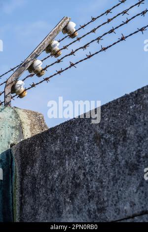 Clôture électrifiée en barbelés au-dessus du mur en béton du camp de concentration de Dachau Banque D'Images