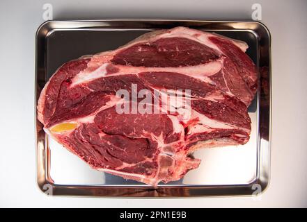 Steak de cowboy cru avec assaisonnements sur fond blanc, œil de côte sur os Banque D'Images